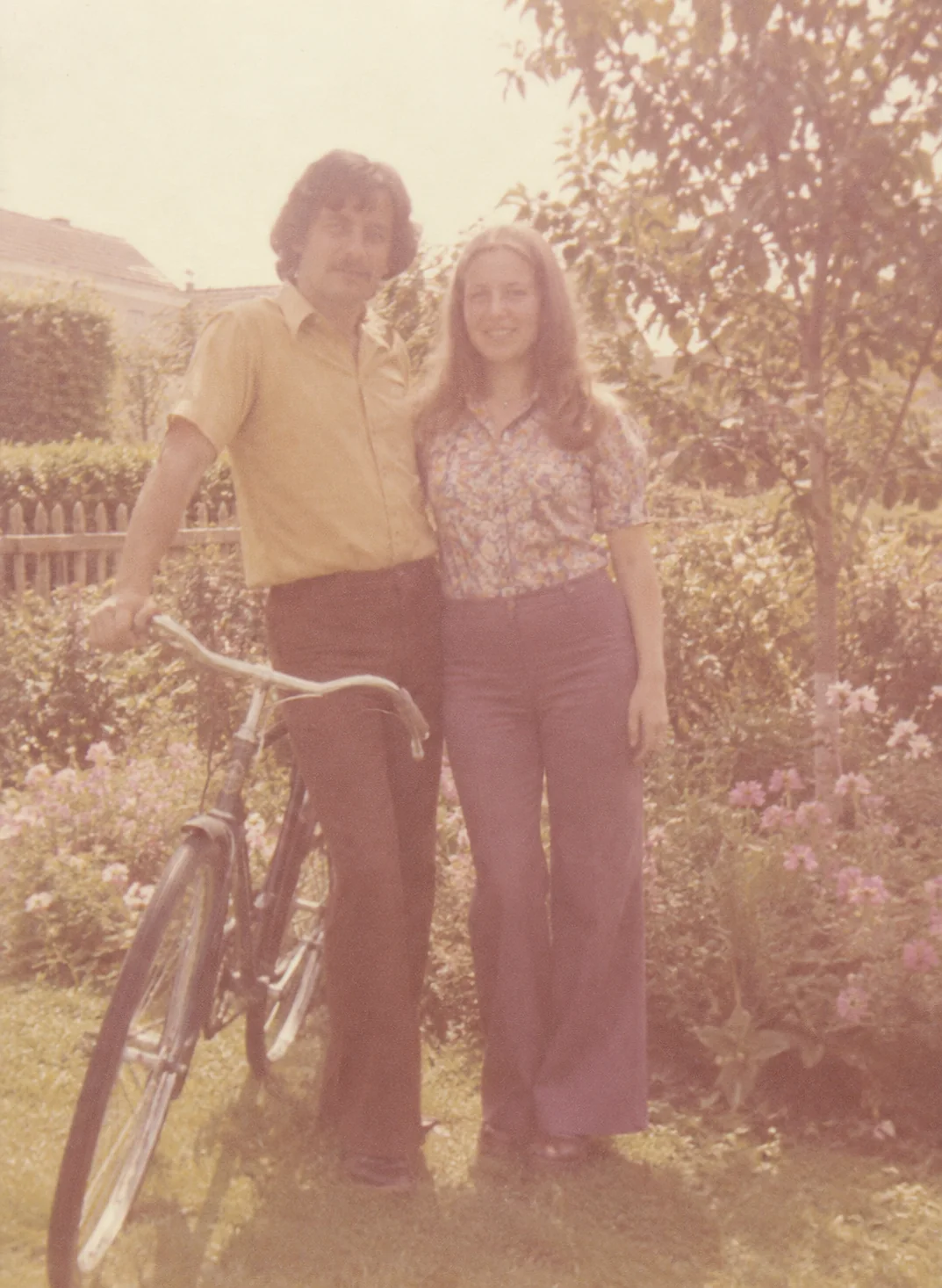 Faded 1970s color photograph of two adults and a bicycle